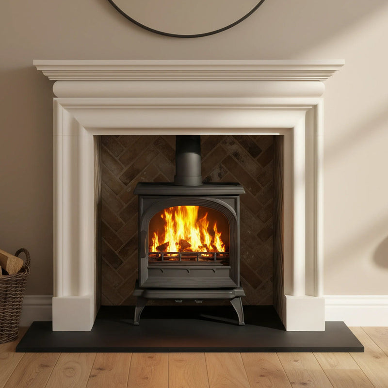 Wood-burning stove in a fireplace with wooden floor and basket of logs.