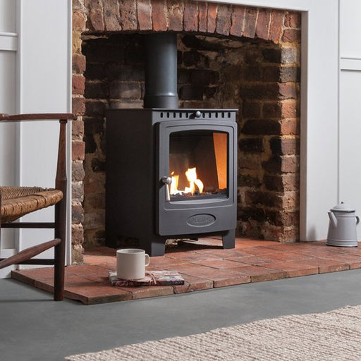 Arada Stove in living room against a brick wall