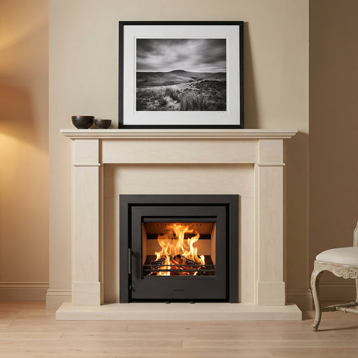 Fireplace with lit fire, framed picture above, lamp to left, and chair to right in a room.