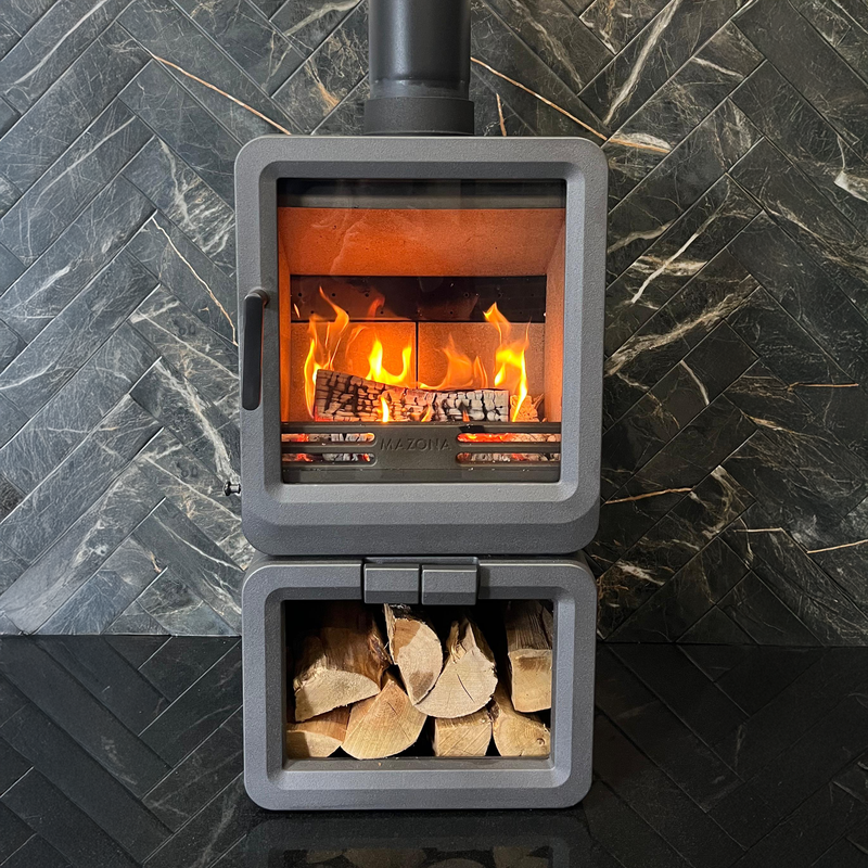Grey wood stove with fire and wood inside, against a stone wall background