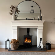 Living room with a fireplace, Mazona Rye 5kW stove, mirror, and decorative items.