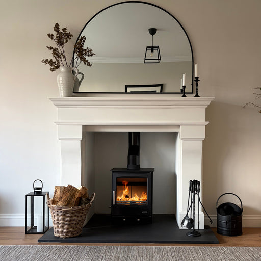 Living room with a fireplace, Mazona Rye 5kW stove, mirror, and decorative items.