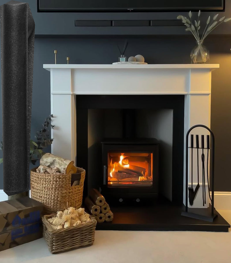 White fireplace with a lit fire, surrounded by decorative items like baskets and a TV above.