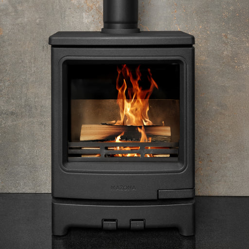 Black stove with flames inside, against a gray concrete wall.